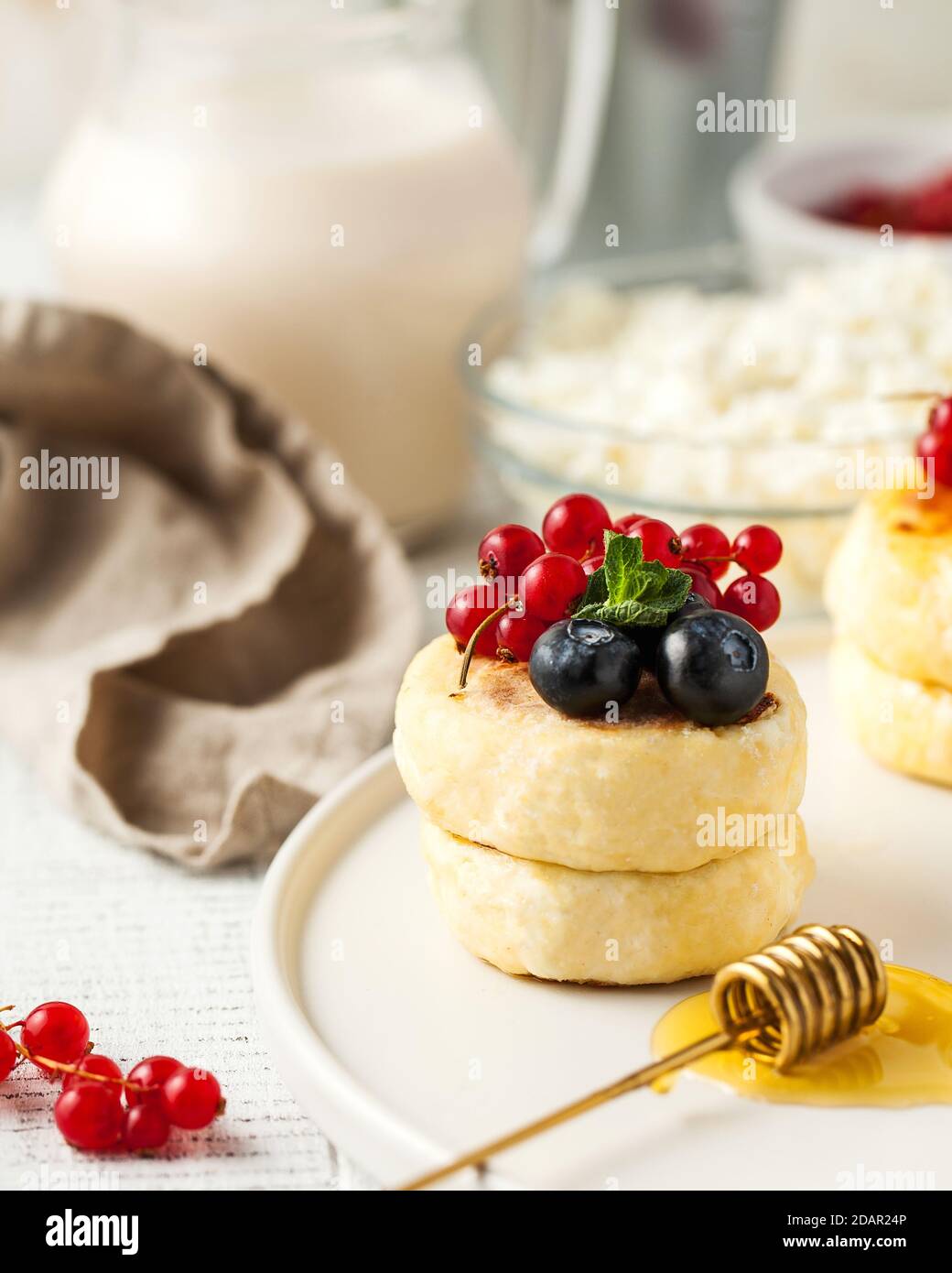 Cheesecakes décorées de baies fraîches et de miel sur une assiette. Menus du petit-déjeuner. Banque D'Images