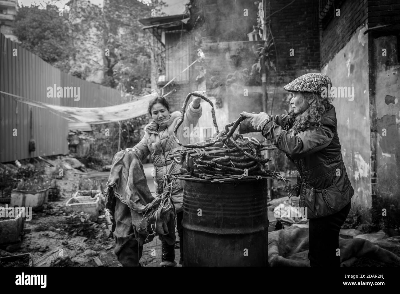 Scène de rue dans un quartier de la vieille ville de Chongqing. Les femmes fument des saucisses maison. Ces districts sont progressivement démolis pour faire de la place Banque D'Images