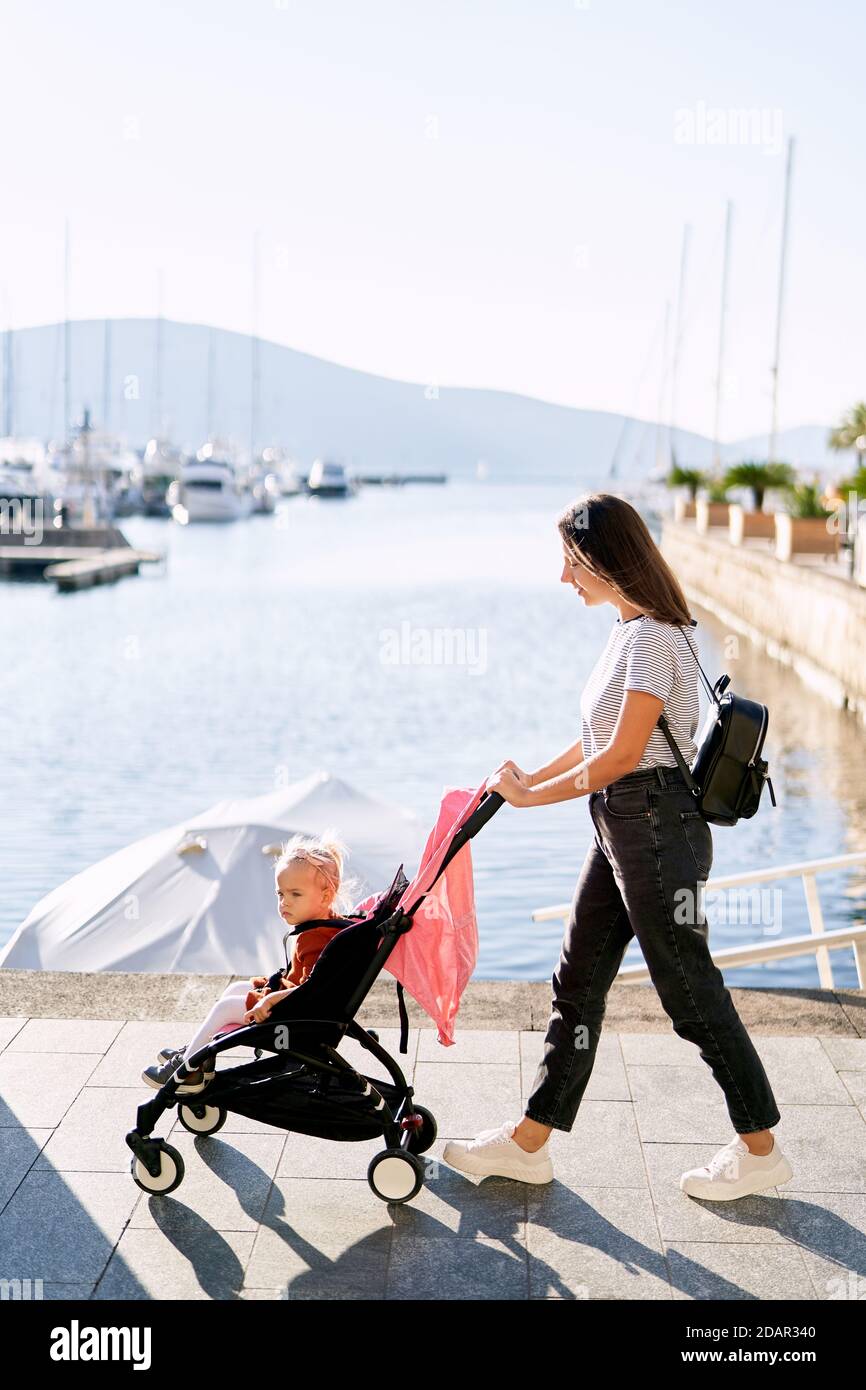 Une Femme Pousse Sa Fille Dans Une Poussette Rose Une Jetee De Bateau Par Une Journee Ensoleillee Photo Stock Alamy