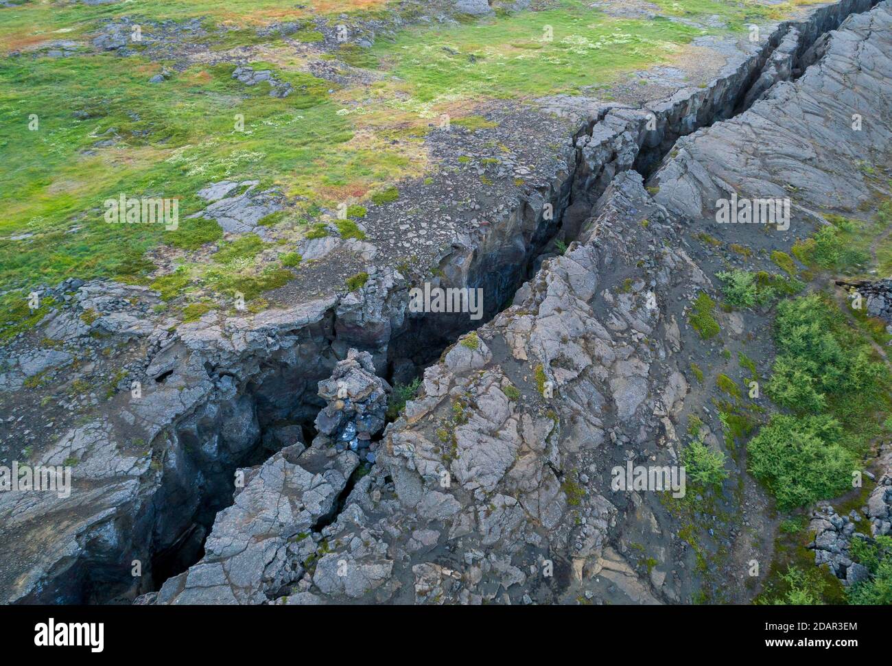 La fissure noire traverse une prairie verte dans la zone de faille, Grjotagja, Skutustaoir, Eystra de Norourland, Islande Banque D'Images