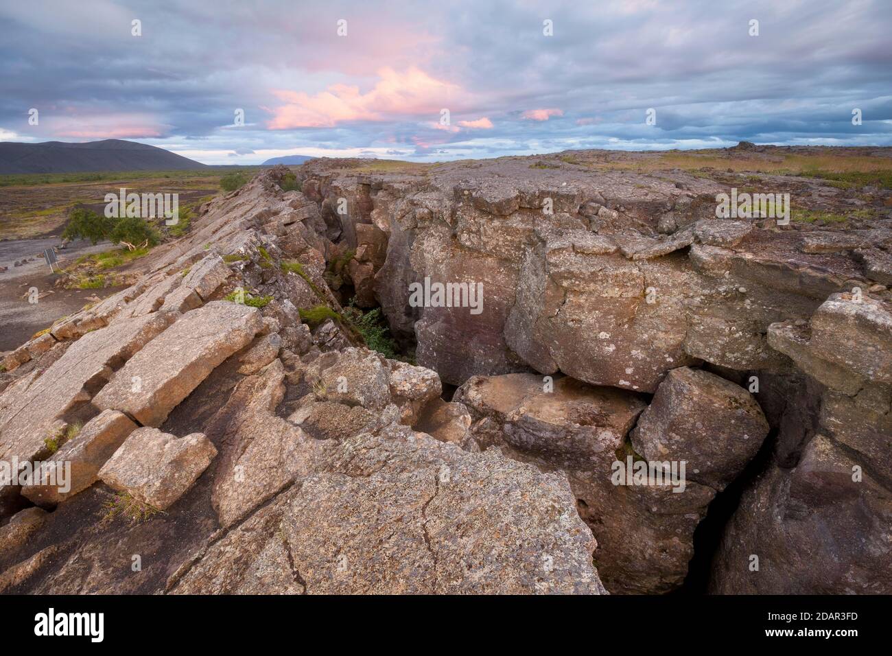 Colonne rouge dans la plaine avec des nuages dramatiques dans le ciel du soir dans la zone de faille, Grjotagja, Skutustaoir, eystra de Norourland, Islande Banque D'Images