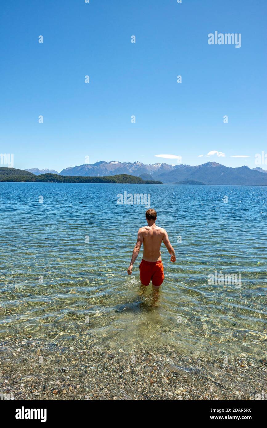 Un jeune homme baigne dans le lac, le lac Manapari, Frasers Beach, Manapouri, Île du Sud, Nouvelle-Zélande Banque D'Images