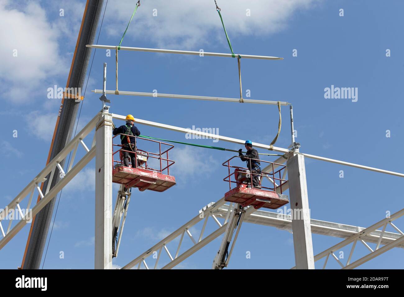Deux ouvriers de la construction sur des plates-formes de travail, assemblant la structure de toit d'une salle logistique, Duisburg, Rhénanie-du-Nord-Westphalie, Allemagne Banque D'Images