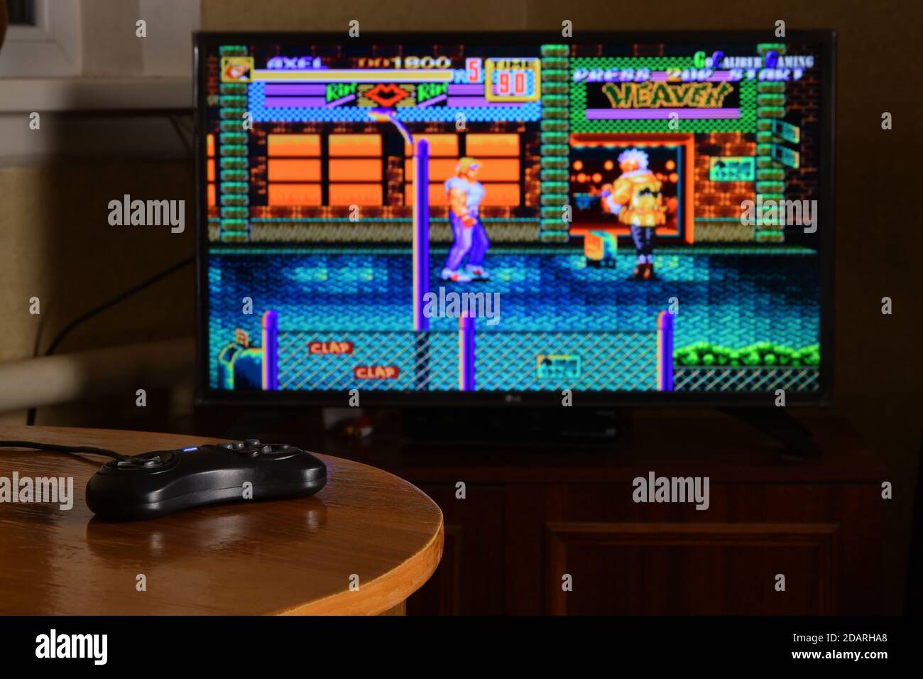 KHARKOV, UKRAINE - NOVEMBRE 12, 2020: Sega méga drive contrôleur de jeu vidéo sur table avec les rues de rage 2 jeu sur grand écran Banque D'Images