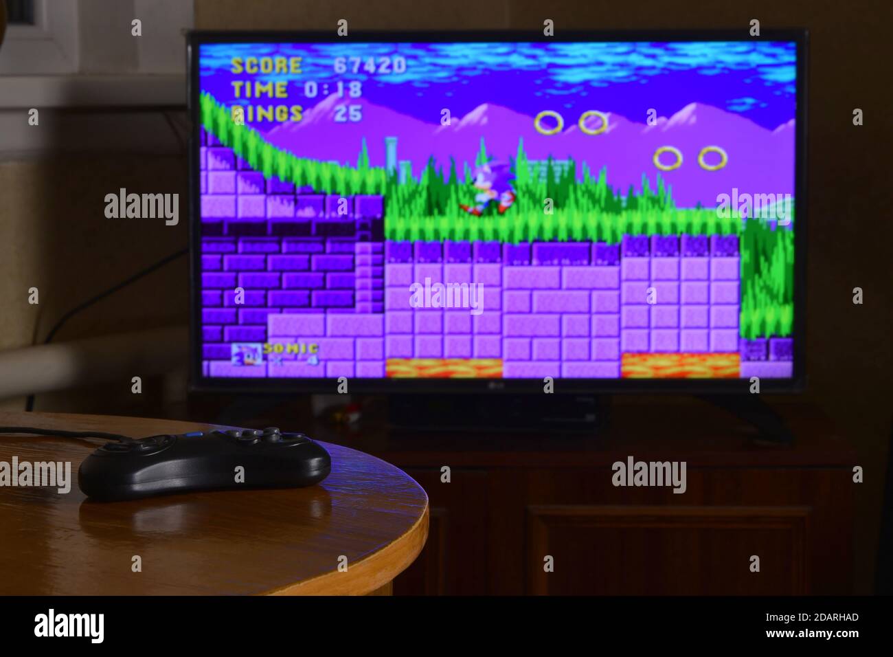 KHARKOV, UKRAINE - NOVEMBRE 12, 2020: Sega méga Drive contrôleur de jeu vidéo sur table avec Sonic le jeu Hedgehog sur grand écran Banque D'Images