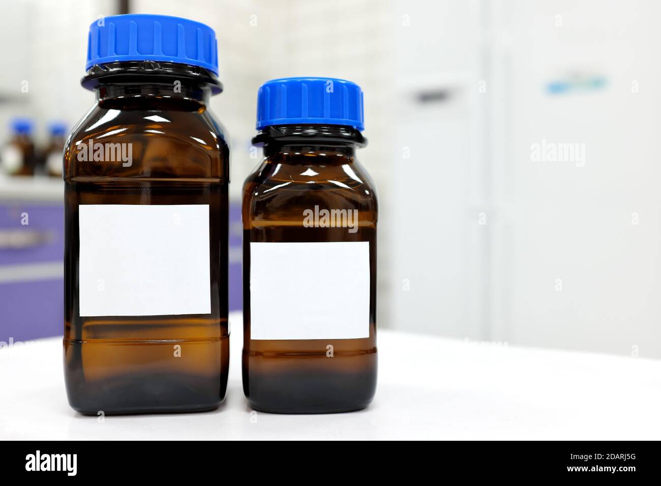 Foyer sélectif de deux flacons de réactif en verre foncé avec inconnu produit chimique liquide transparent à l'intérieur et étiquette vierge dans un constituant chimique laboratoire Banque D'Images