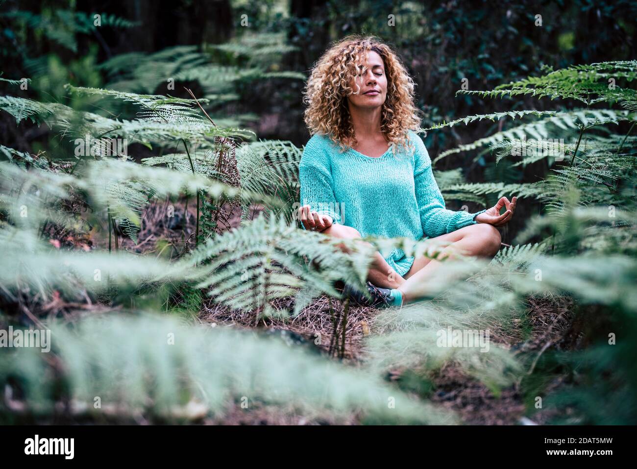 Détendue belle dame ne méditation assis au milieu de nature plante en plein air - les gens en pleine conscience méditent l'activité en appréciant extérieur naturel Banque D'Images