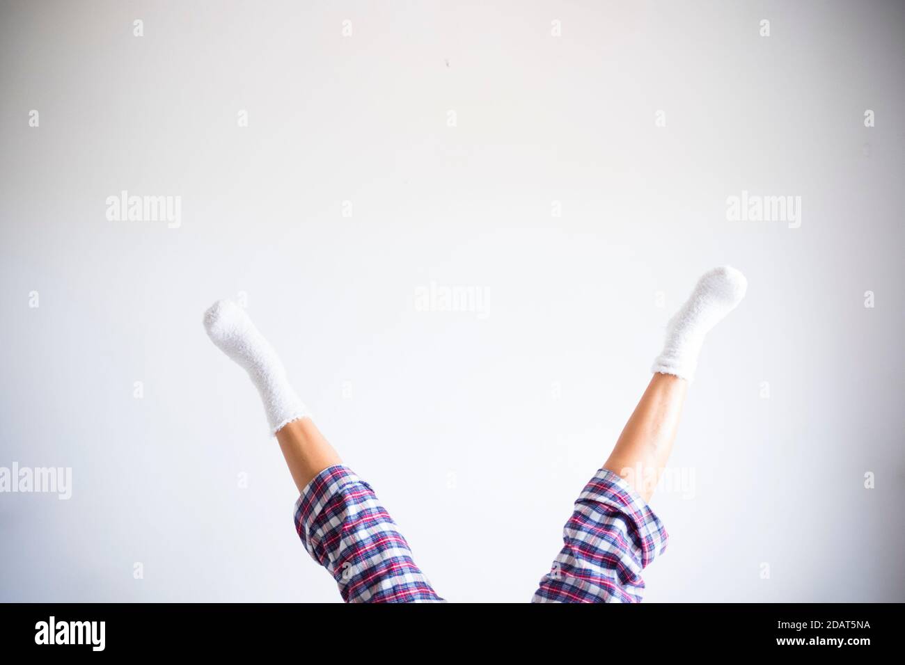 Femme jambes vers le bas en position inverse avec mur blanc de la pièce contexte - concept d'exercices de forme physique à la maison et sain drôle de vie personnes - codysp Banque D'Images