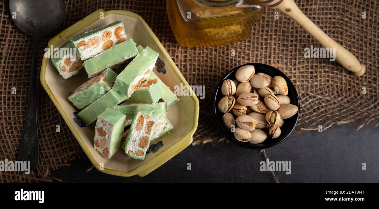Nougat bio faites avec du miel, pistache, noisette, noix et amandes, sur un fond sombre. rustique Banque D'Images
