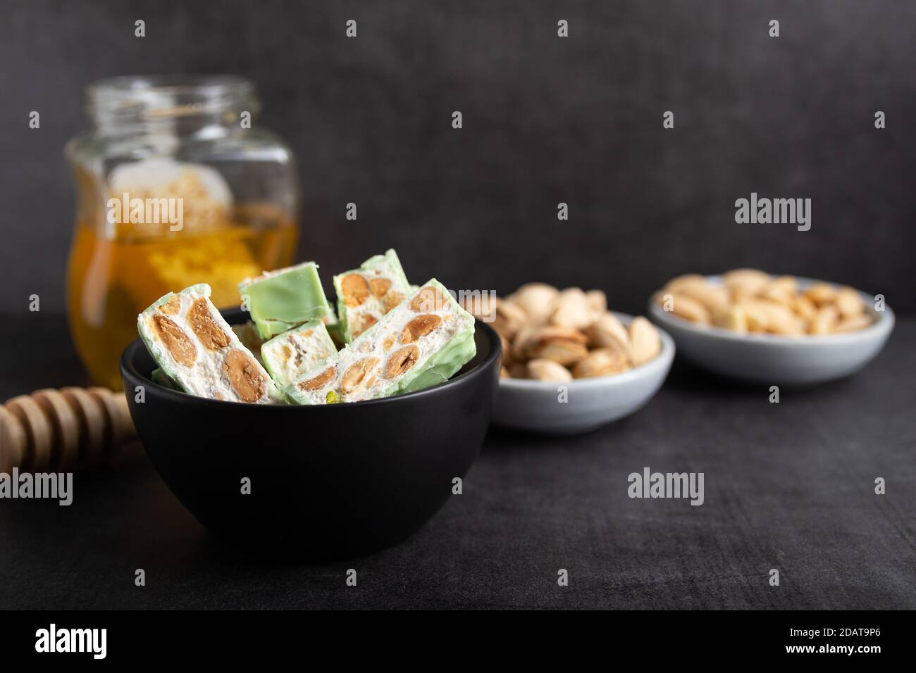Nougat bio faites avec du miel, pistache, noisette, noix et amandes, sur un fond sombre. rustique Banque D'Images