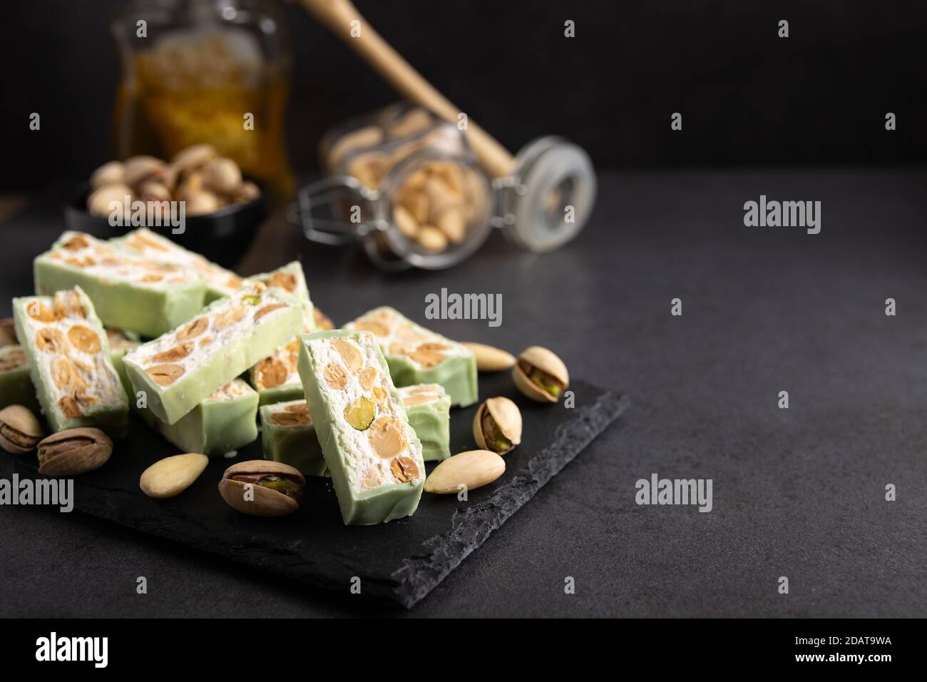 Nougat bio faites avec du miel, pistache, noisette, noix et amandes, sur un fond sombre. rustique Banque D'Images