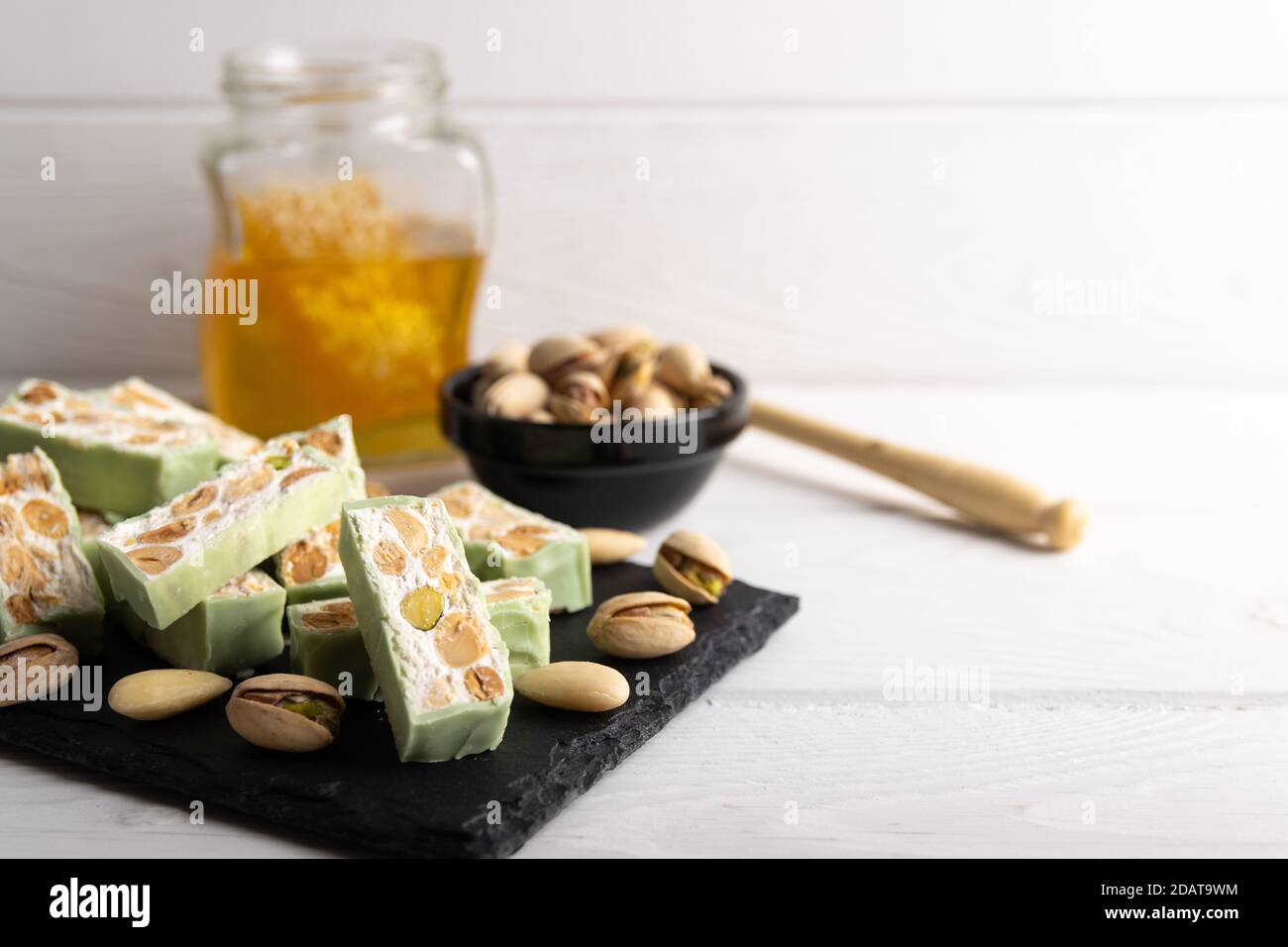 Nougat bio faites avec du miel, pistache, noisette, noix et amandes, sur un fond blanc. Banque D'Images