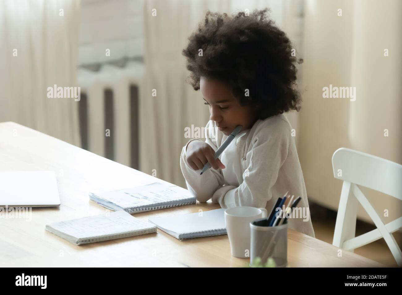 Petite fille afro-américaine attentionnés qui étudie à la maison Banque D'Images