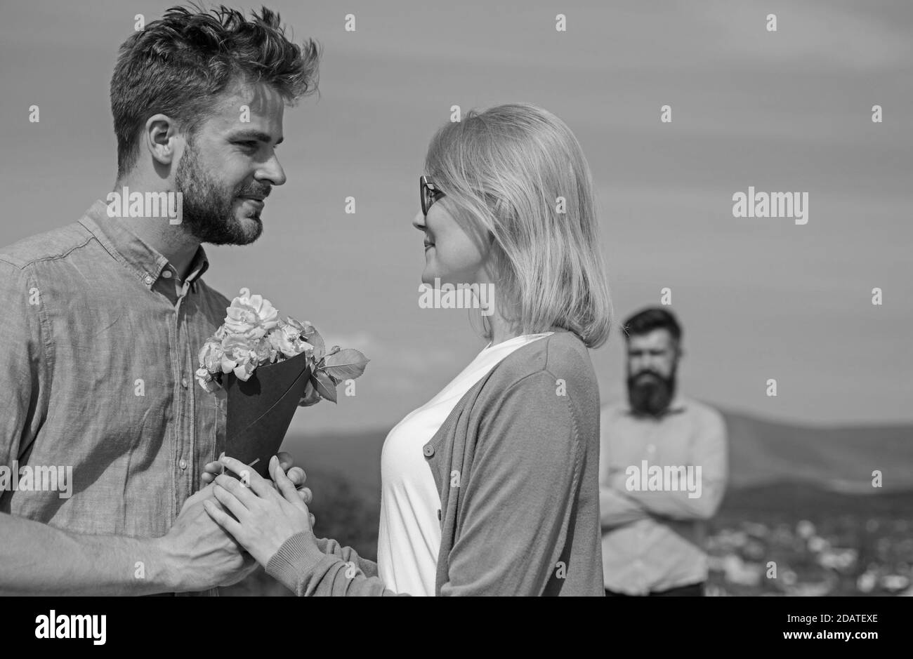 Couple avec bouquet de fleurs date romantique. Nouvel amour. Couple amoureux datant de plein air ensoleillé jour, ciel fond. Ex partenaire regarder fille commence heureux amour relations. Ex mari jaloux sur fond. Banque D'Images
