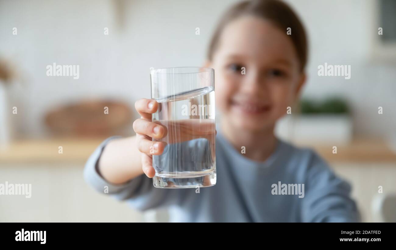 Gros plan petite fille tenant le verre d'eau, offrant à l'appareil photo Banque D'Images