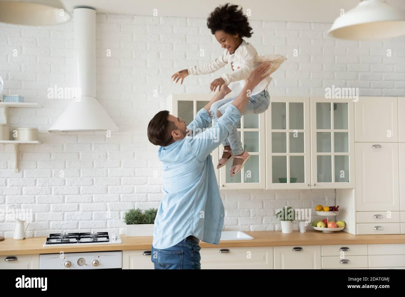 Un jeune père excité lance une petite fille afro-américaine dans l'air Banque D'Images