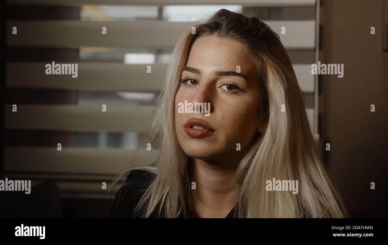 Jeune blond charmant jolie blonde cheveux femme regardant l'appareil photo au bureau ou à la maison, vêtue de blond noir Banque D'Images