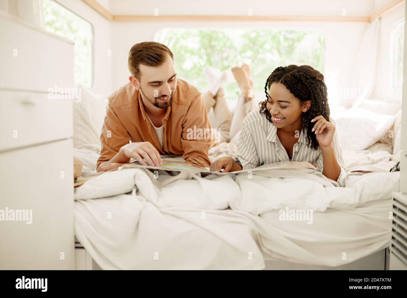 Couple amoureux regardant sur la carte dans un lit de camping, remorque Banque D'Images