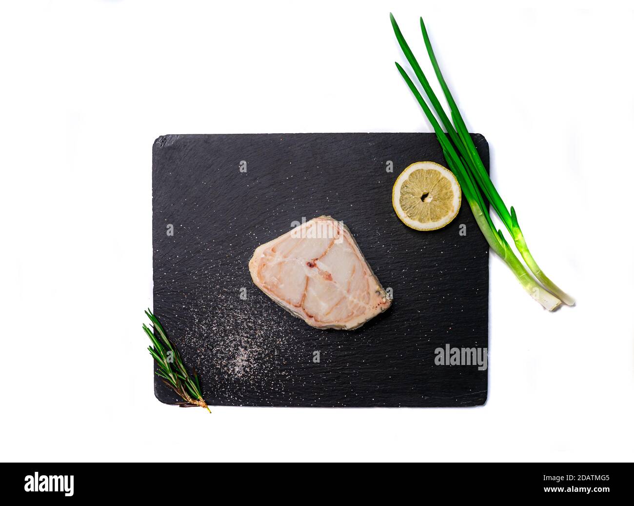 Steak de poisson-chat cru sur le plateau de schiste avec romarin, oignon vert et citron. Isolé. Banque D'Images