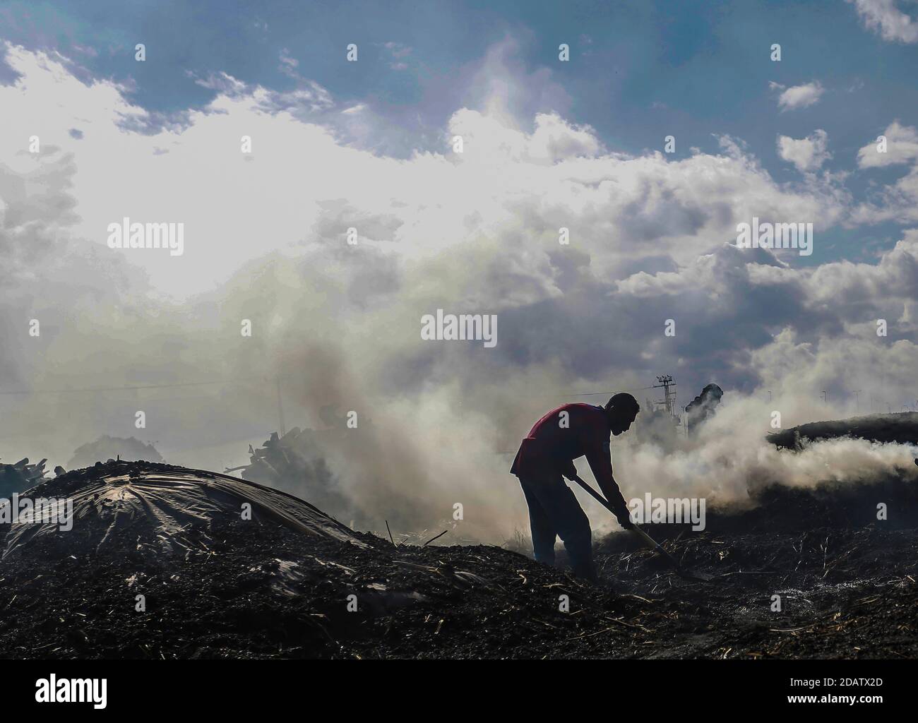 Un ouvrier du charbon palestinien jette du sable à l'installation de production d'Al-Hattab, à l'est du camp de réfugiés de Jabalia, au nord de la ville de Gaza. L'installation de charbon de Habash est le plus grand producteur de la bande de Gaza. Sept hommes travaillent tout au long de l'année, en particulier pendant l'hiver et les vacances où la demande de charbon est élevée. Tandis que les travailleurs réduisent différents types d'arbres, le bois de chauffage est couramment utilisé pour fabriquer du charbon de bois. Le citrus est très bénéfique et le plus cher, mais les travailleurs de habash ne l'installent pas sur ce type seulement sur lui et traitent des variétés disponibles telles que certains Kenya ou des olives. Après la récolte du Banque D'Images
