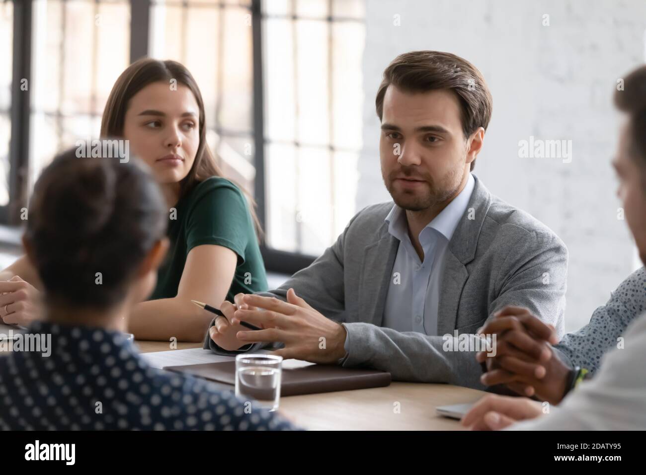 Une équipe d'affaires diversifiée assise dans la salle de réunion à l'écoute de ses collègues Banque D'Images