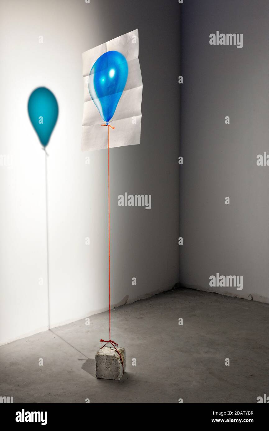 Une feuille de papier avec l'image d'un ballon reflète son ombre sur un mur blanc. Banque D'Images