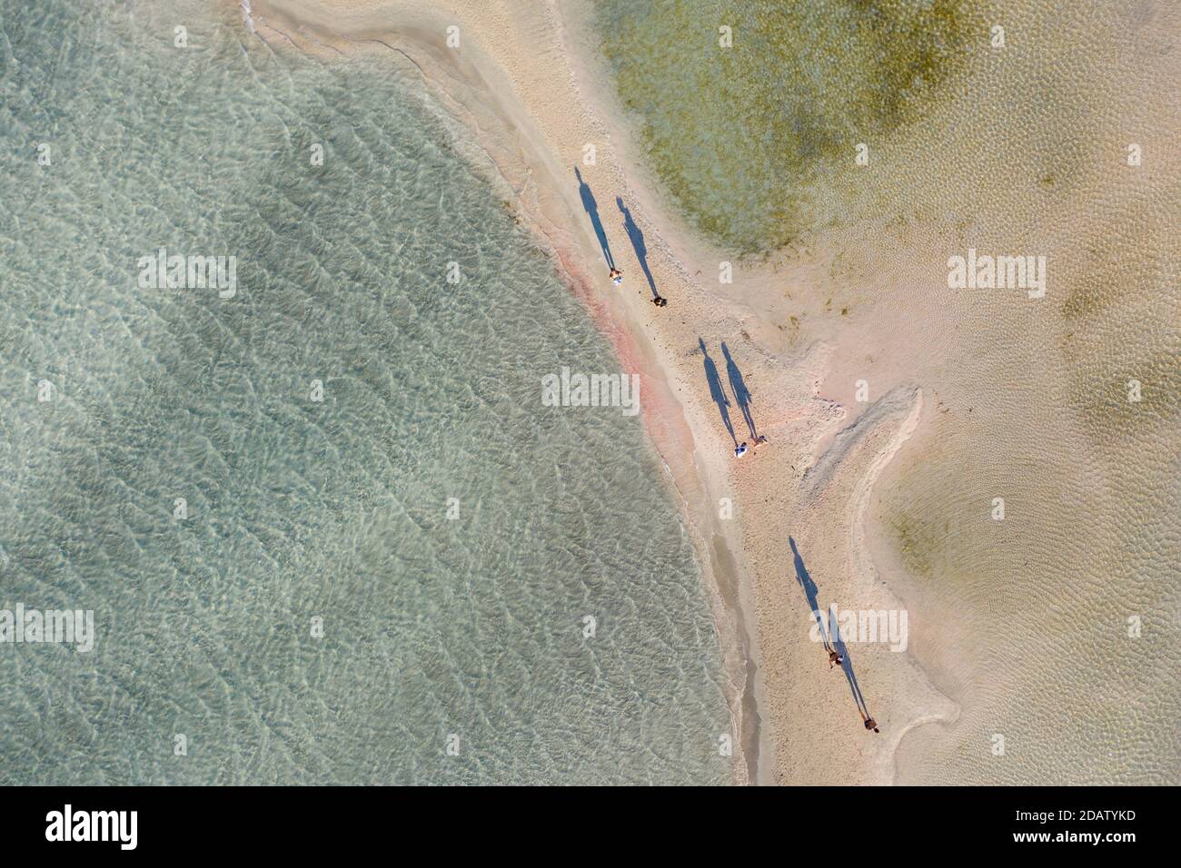 Vue aérienne des personnes marchant et jetant de longues ombres sur le bar de sable de la plage d'Elafonisi, l'une des destinations touristiques les plus populaires dans les sud du pays Banque D'Images