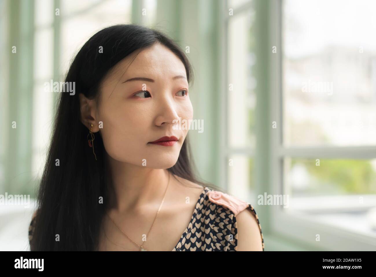 Une femme chinoise regardant par une fenêtre à l'intérieur d'un salon dans le musée d'art walters à baltimore maryland. Banque D'Images