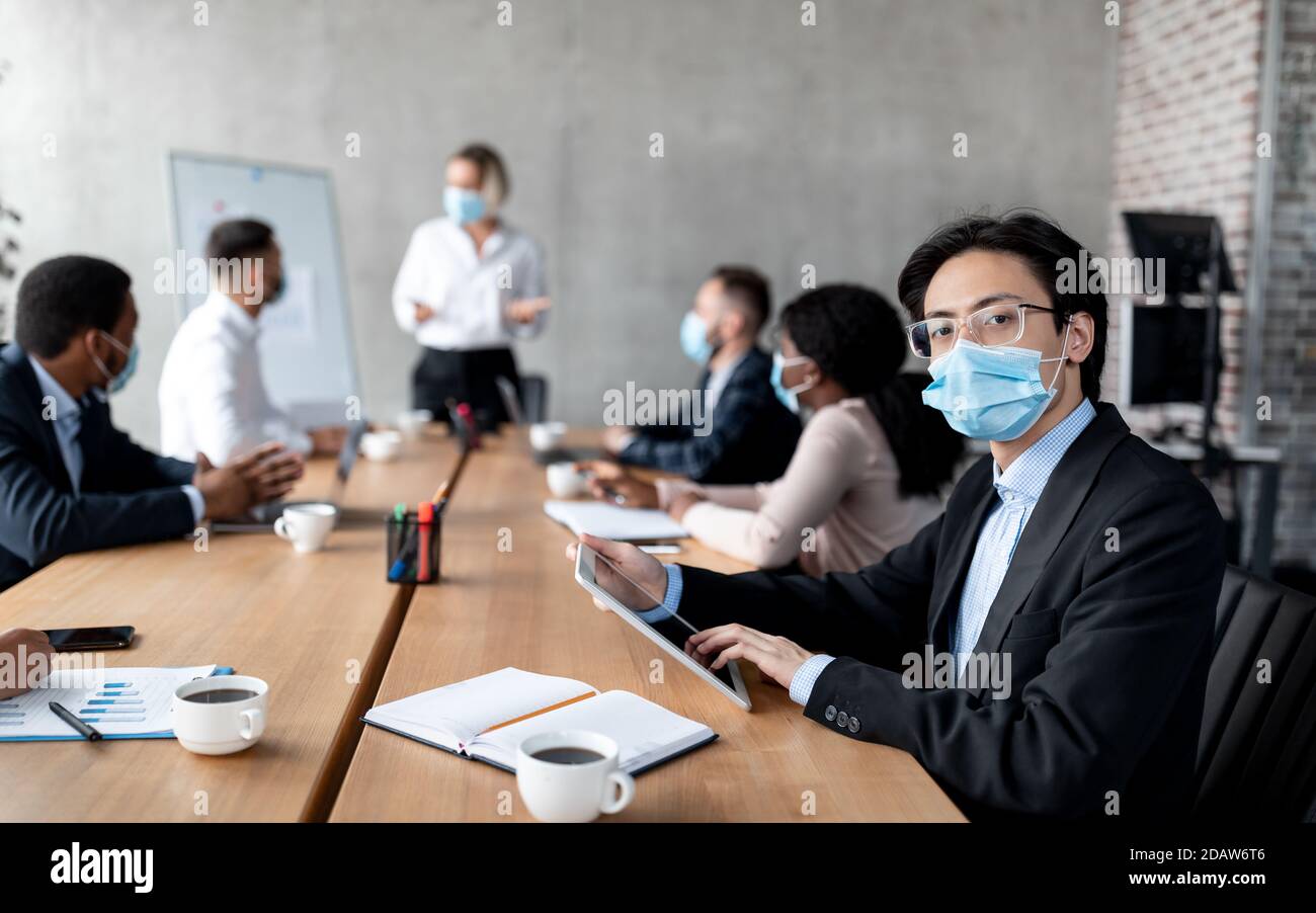 Homme d'affaires asiatique Entrepreneur en masque de visage assis dans le bureau moderne Banque D'Images