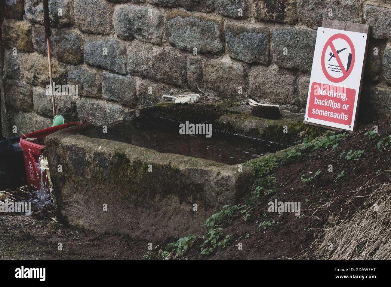 Un fermier du Yorkshire avec un sens de l'humour place un signe de non plongée près d'un vieux bac en pierre dans sa ferme, Burley Woodhead, Royaume-Uni Banque D'Images