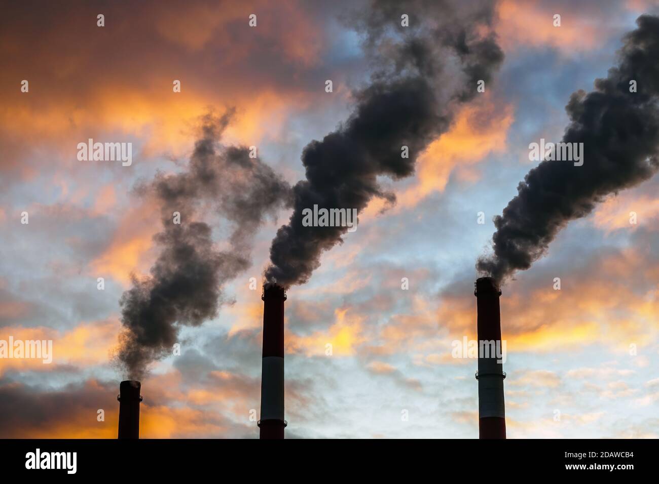 Trois cheminées fumeurs sur fond de ciel spectaculaire et coloré. Le concept de pollution de l'air et de l'environnement. Banque D'Images