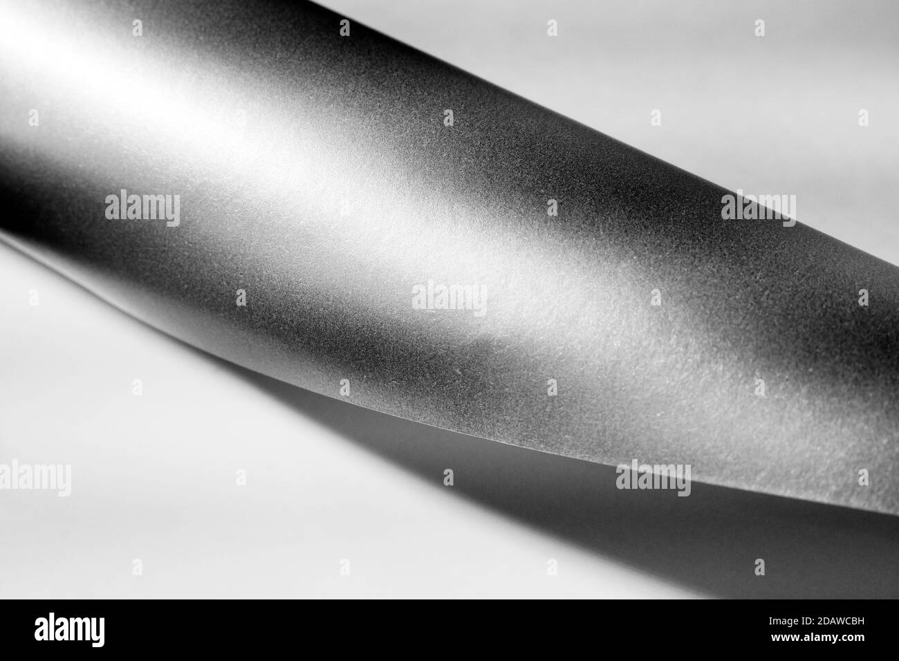 Ligne de papier à courbe rapprochée, arrière-plan noir et blanc abstrait minimal, mise au point sélective. Banque D'Images