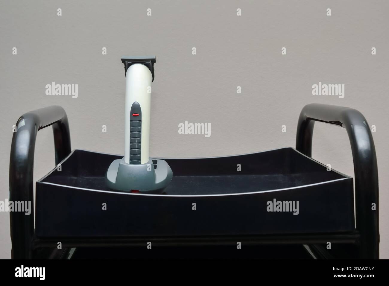 une tondeuse à cheveux sans fil, préparée pour le travail, se trouve dans le station de charge sur le chariot de coiffeur Banque D'Images