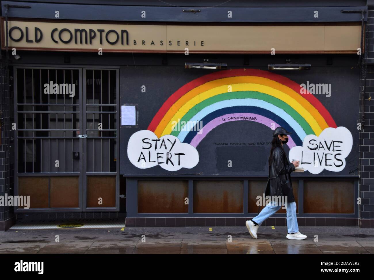 Une femme avec un masque facial protecteur passe devant un panneau Stay Alert, Save Lives Rainbow à Soho, Londres, pendant le deuxième confinement national en Angleterre. Banque D'Images