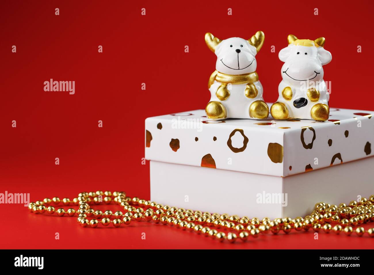 Le jouet du nouvel an d'un taureau et d'une vache avec un cadeau sur fond rouge. Banque D'Images