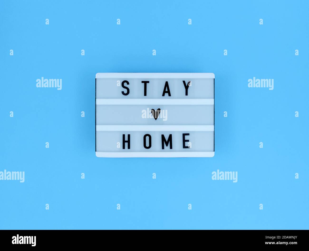 Boîte lumineuse avec citation « rester à la maison » sur fond bleu. Banque D'Images