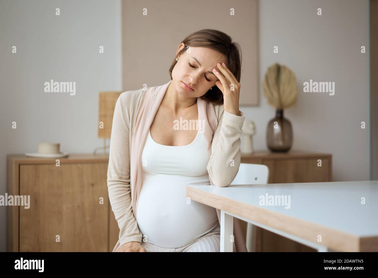 Femme enceinte souffrant de maux de tête assis à la table Banque D'Images