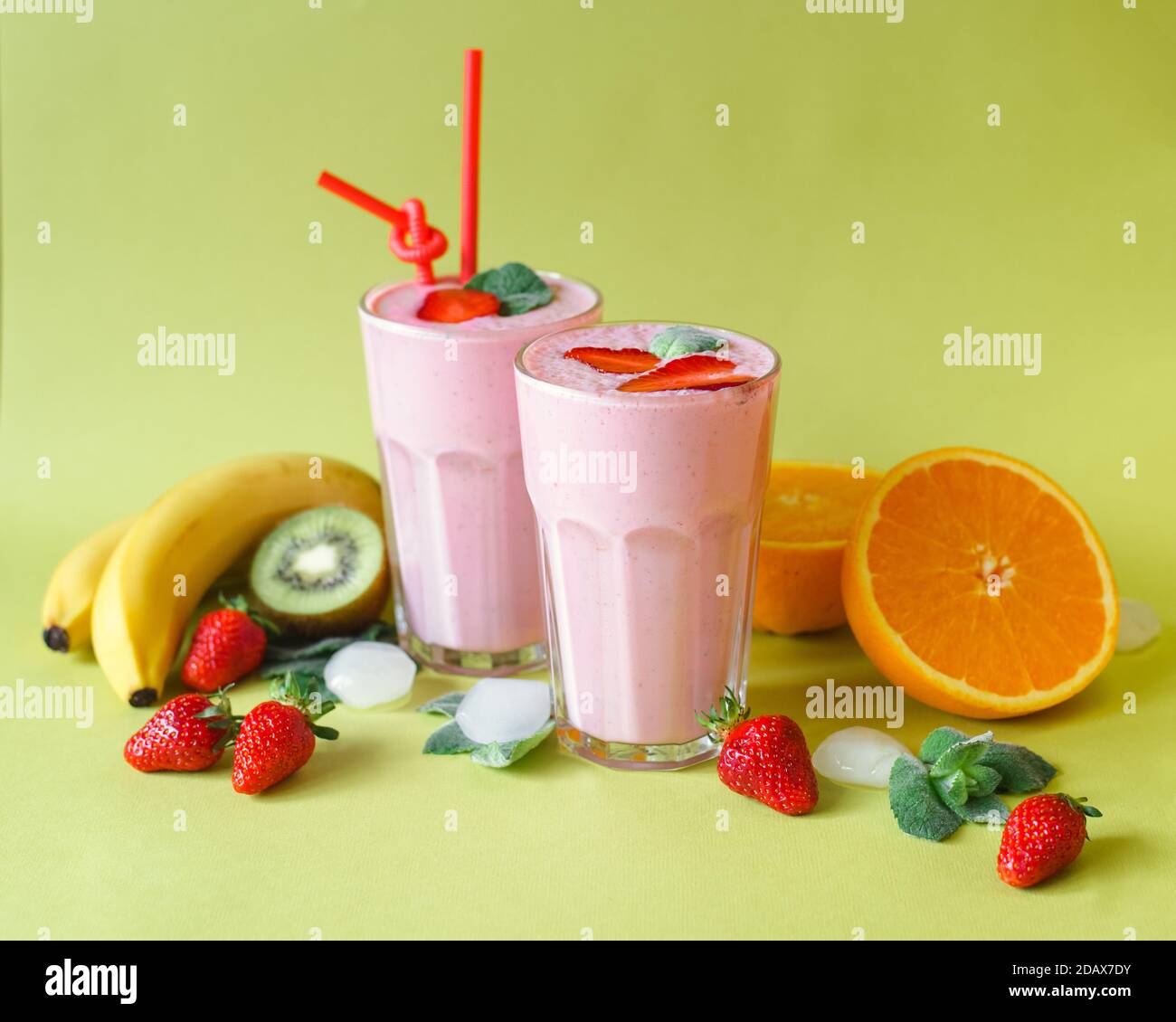 deux verres de cocktail avec menthe et fraises sur le dessus. autour de différents fruits et glace (banane, orange, kiwi, fraises) Banque D'Images