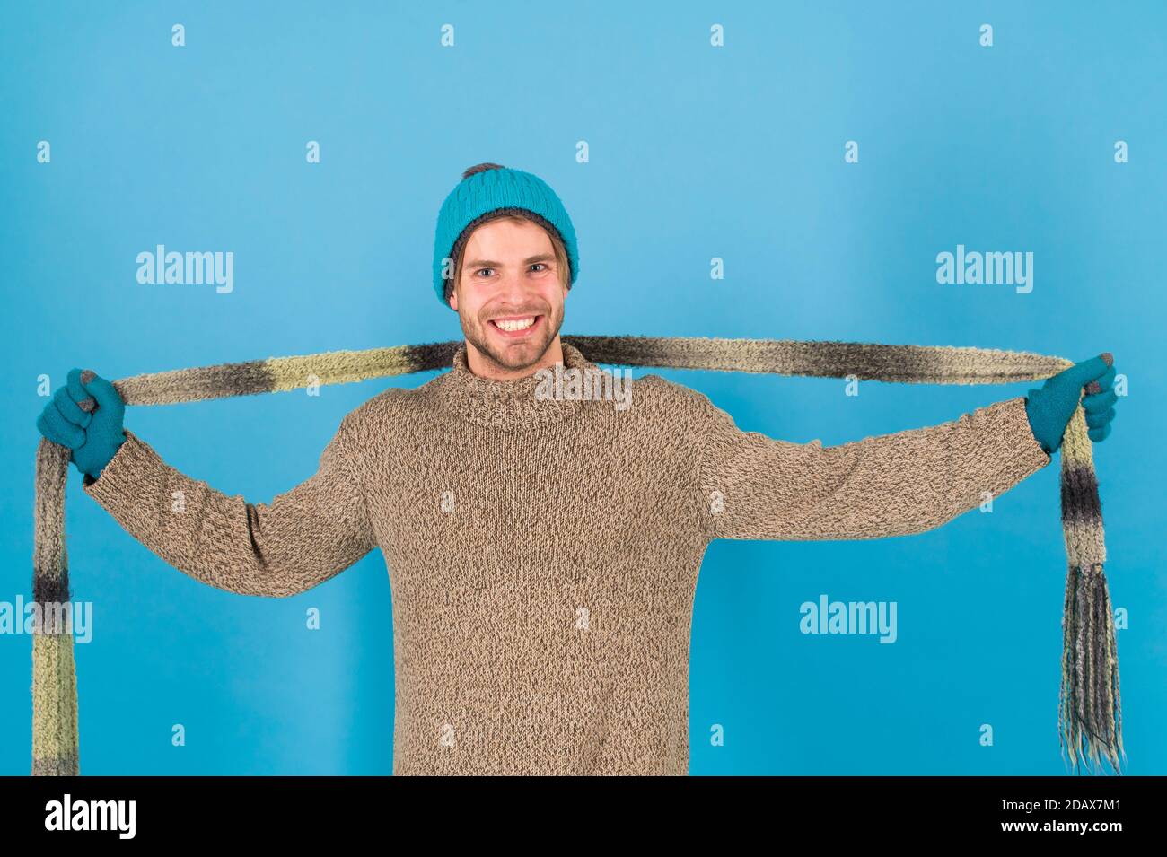 Réchauffer les froides journées d'écharpe. Homme heureux porter une écharpe. Beau gars sourire avec foulard en mains. Accessoire de mode pour l'hiver. Tricot chic foulard à rayures. Banque D'Images