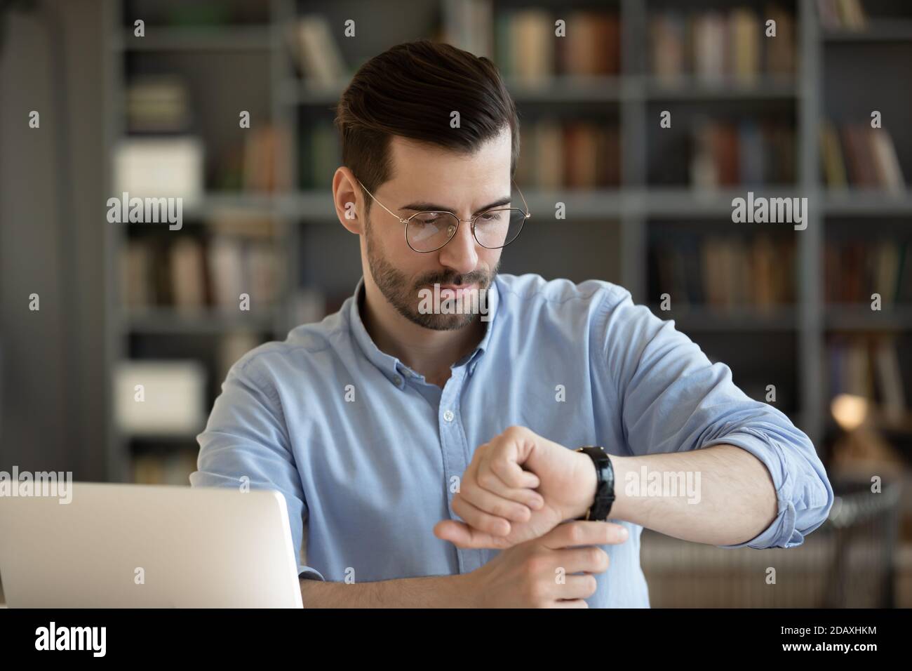 Un homme d'affaires regarde la montre-bracelet vérifie l'heure sur le lieu de travail Banque D'Images