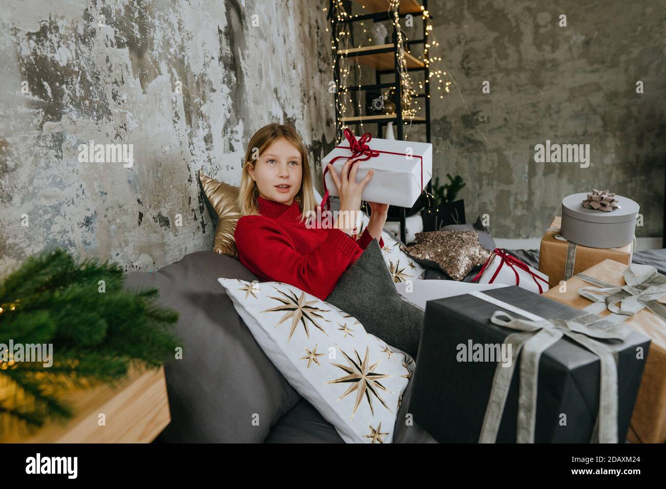 Fille surpisée tenant une boîte cadeau de Noël sur le lit dans la chambre Banque D'Images