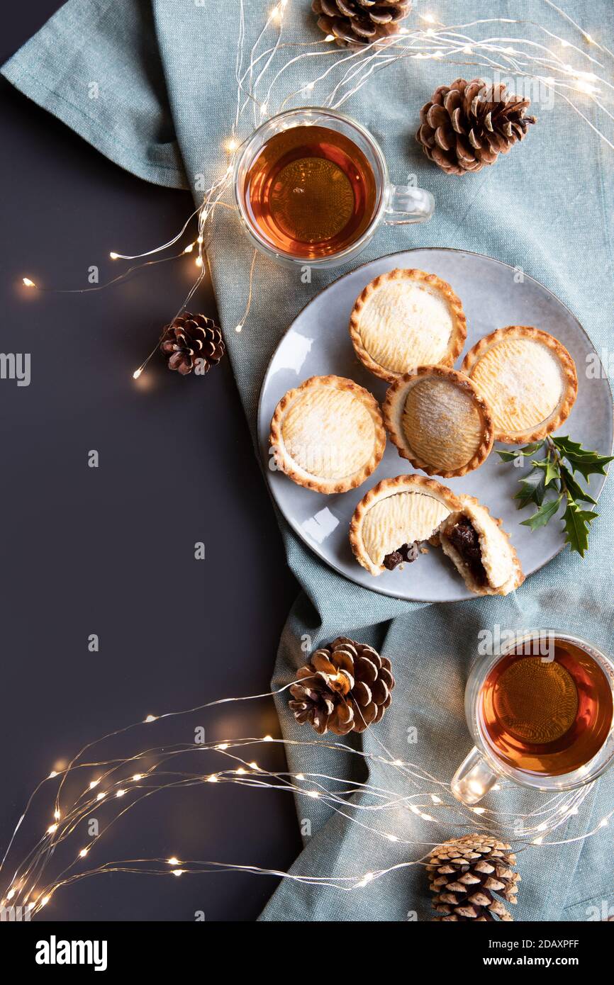 hachez les chaussons sur une assiette et les tasses avec du thé noir tiré par le dessus avec un espace de copie. Une tarte à la menthe est une tarte traditionnelle de Noël, remplie d'un mélange de fruits secs et d'épices Banque D'Images