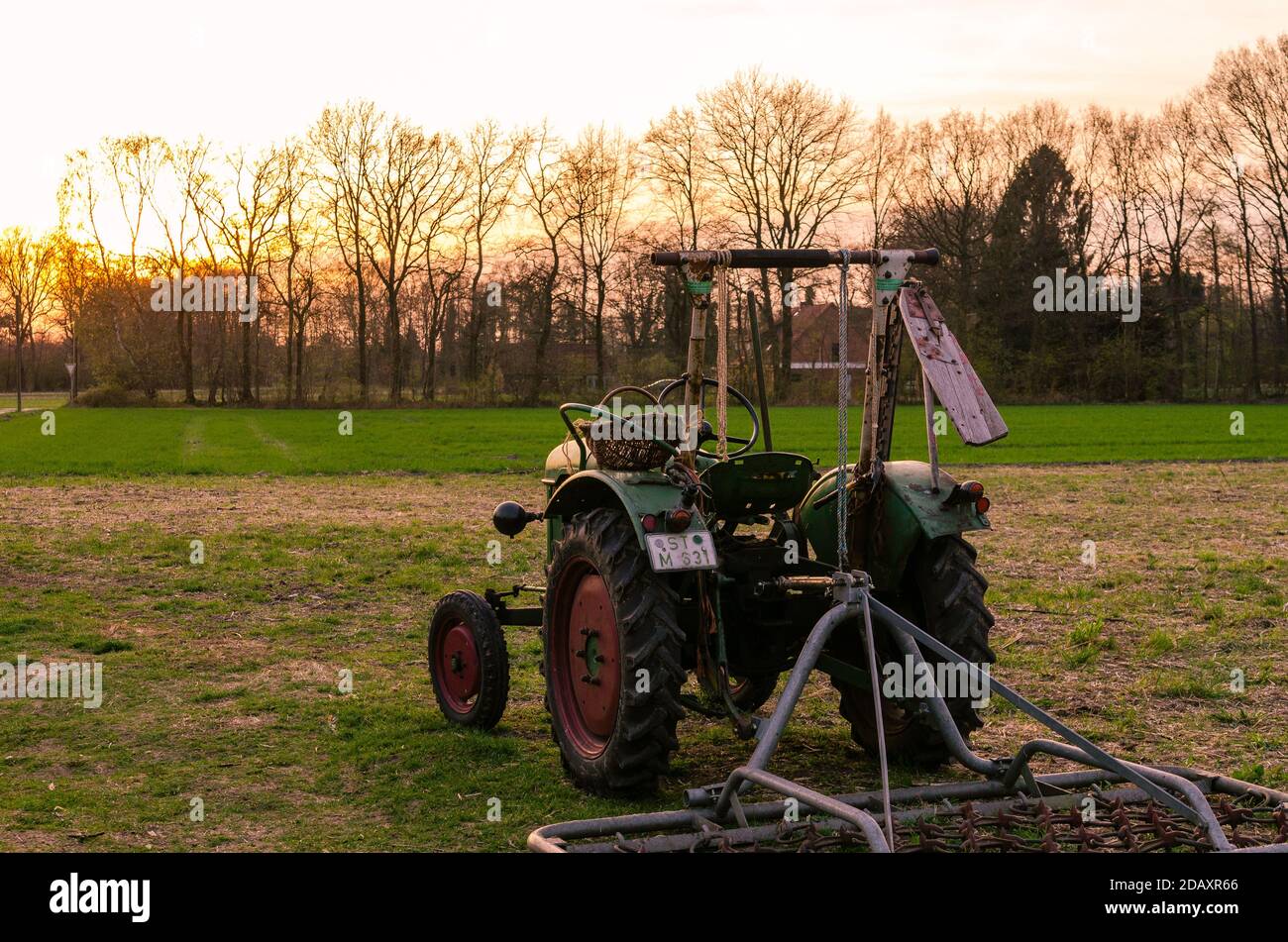 Vieux tracteur sur la prairie au coucher du soleil Banque D'Images