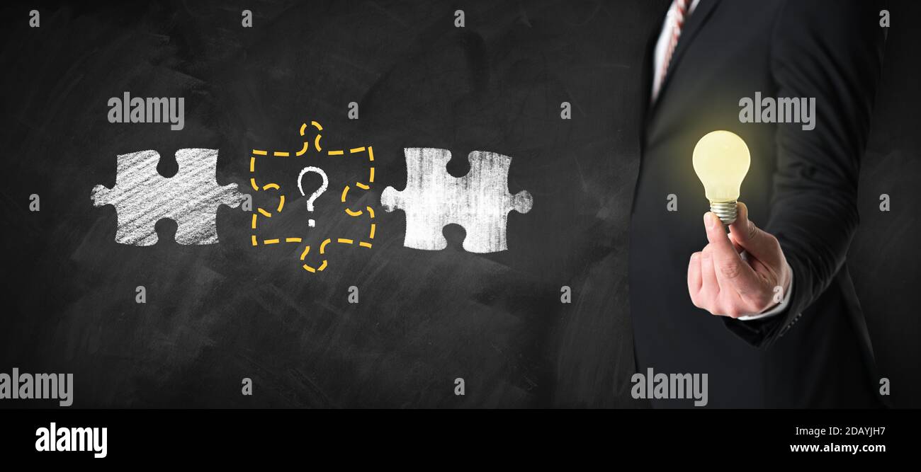 homme d'affaires tenant une ampoule allumée devant un tableau noir Banque D'Images