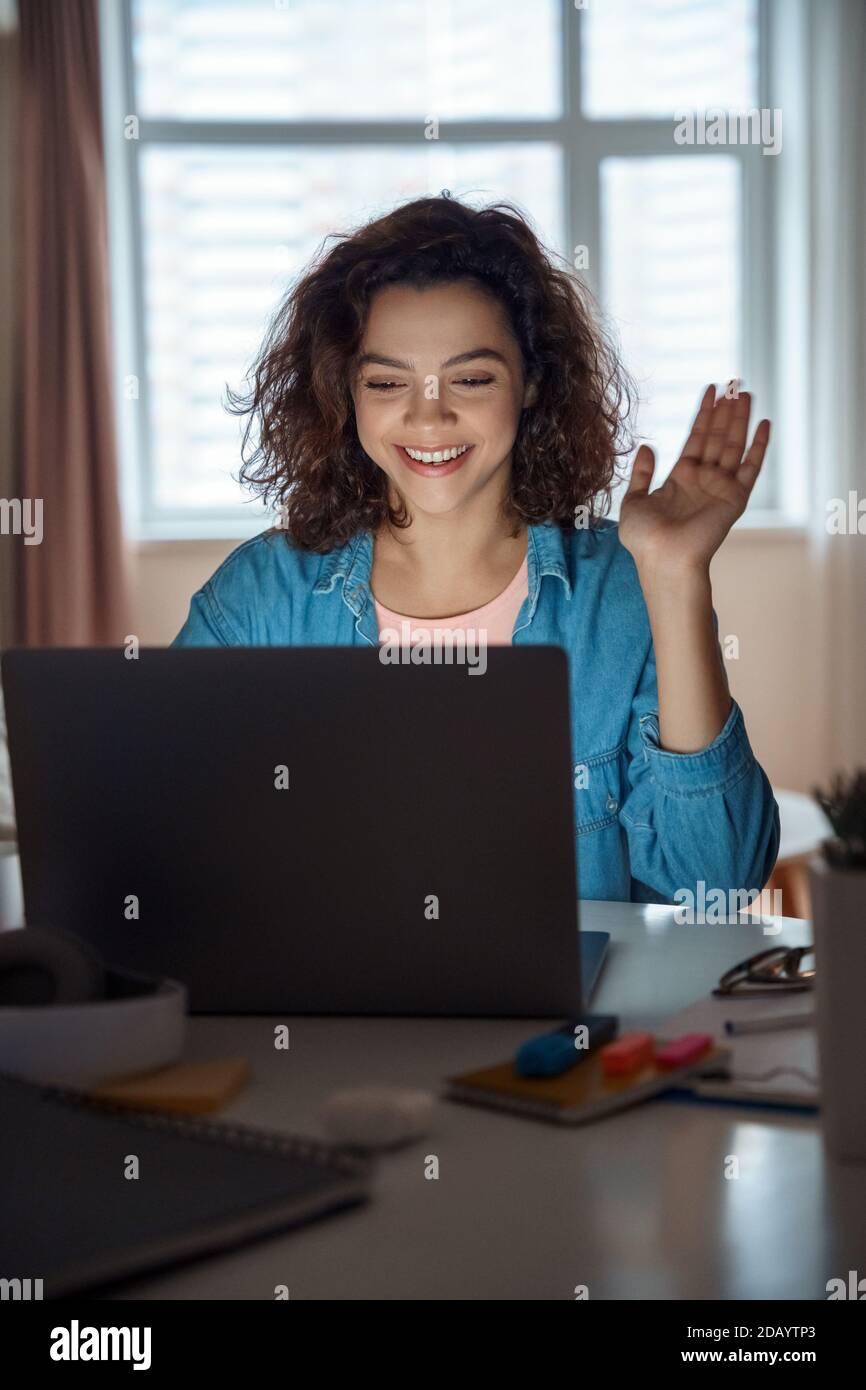 Bonne jeune femme latine travaillant en ligne sur ordinateur portable à la maison. Banque D'Images
