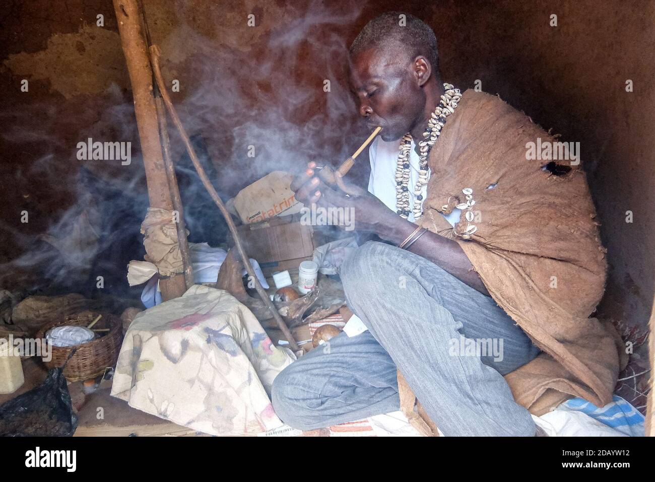 Lubale Bamafamu Idinda, un guérisseur traditionnel, allume un tuyau dans son sanctuaire de Jinja, en Ouganda, pour commencer une cérémonie visant à évoquer les esprits et les ancêtres. Banque D'Images