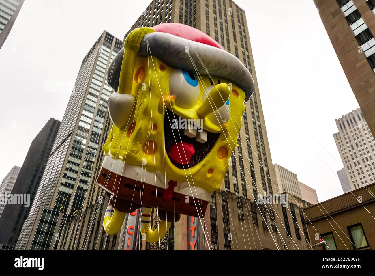 Le ballon SpongeBob Squarepaants flotte dans l'air pendant l'action de grâce de Macy Parade de jour le long de l'avenue des Amériques avec radio Music Hall en arrière-plan Banque D'Images