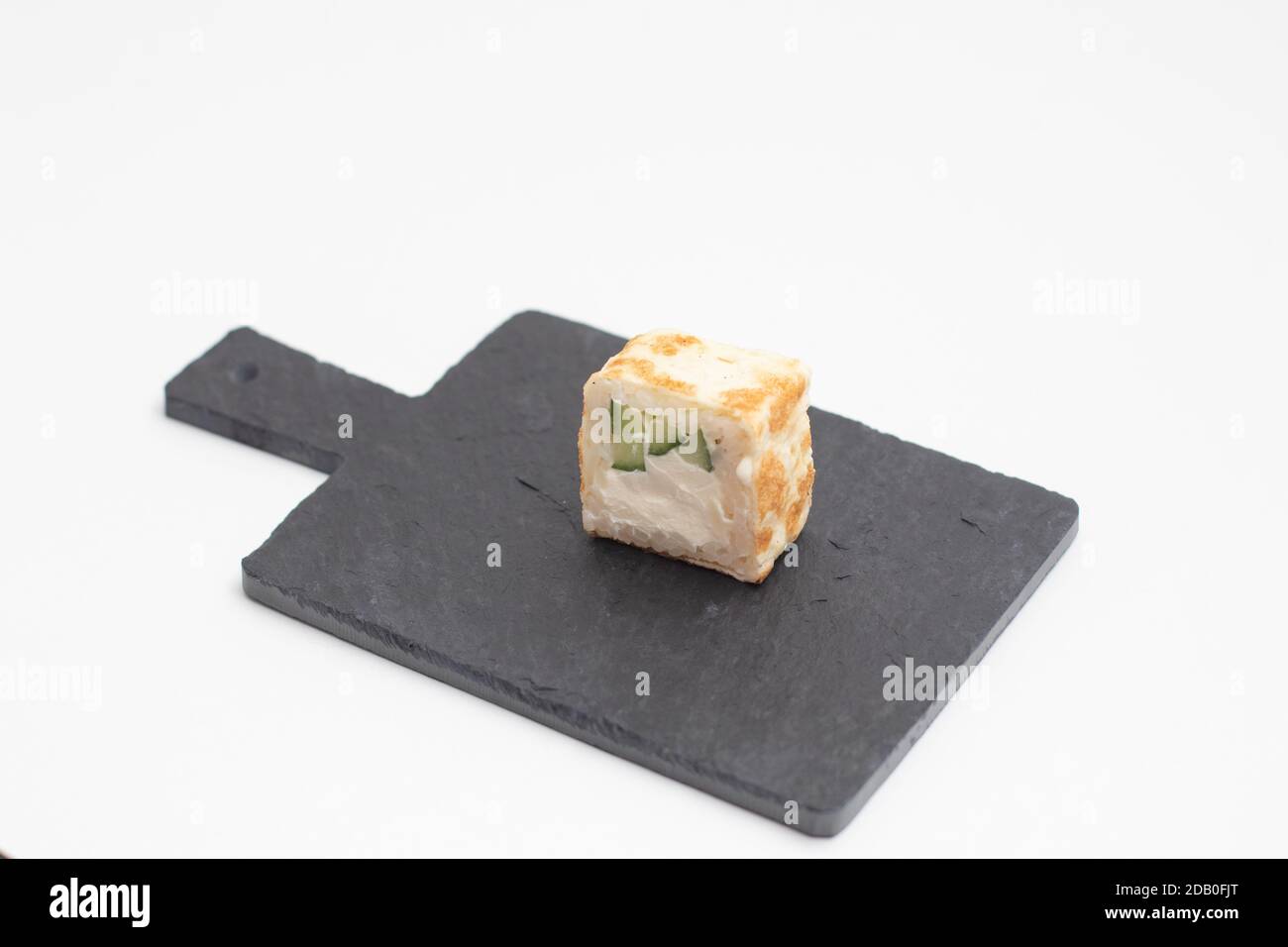 Les sushis roulent dans une crêpe aux œufs sur une planche en ardoise noire. Banque D'Images