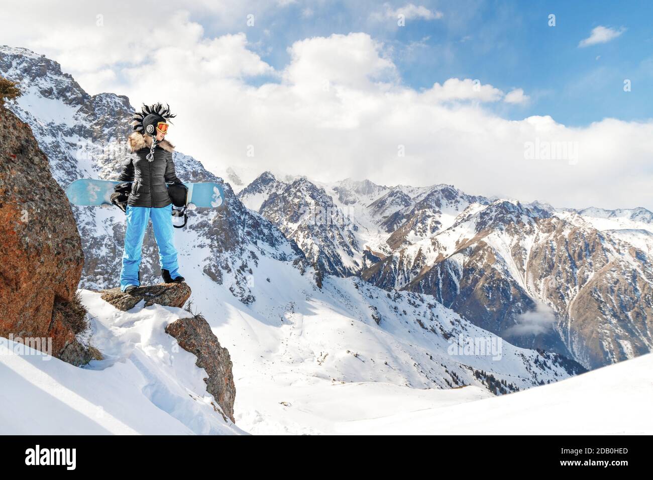 Meilleure photo épique de sport d'hiver extrême avec une jeune femme snowboarder dans un drôle chapeau mohawk dans les montagnes rocheuses. Banque D'Images