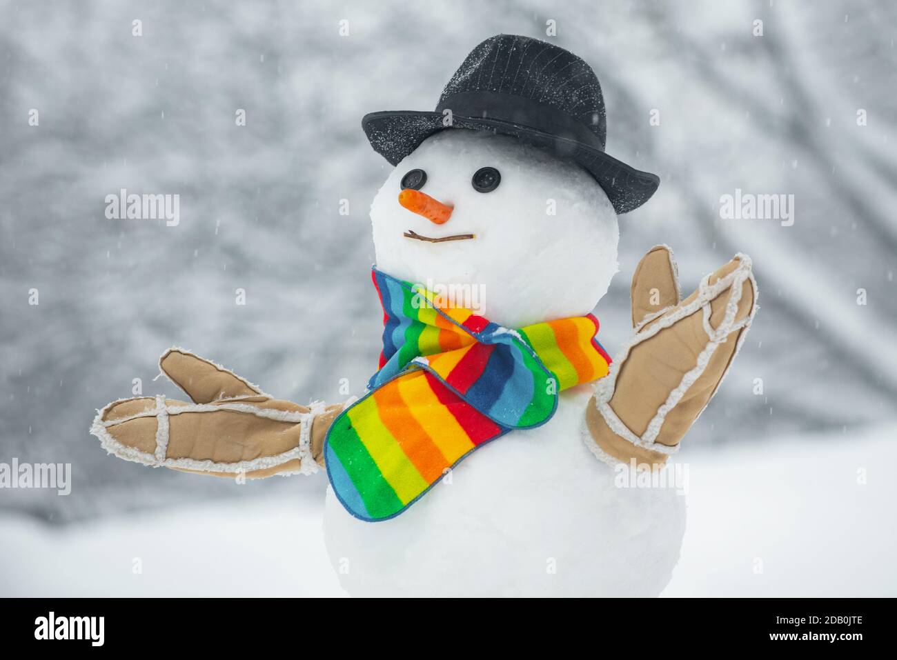 Joyeux bonhomme de neige souriant par beau temps d'hiver. Bonhomme de neige fait main dans la neige en plein air. Bonhomme de neige dans un foulard et un chapeau. Bonhomme de neige mignon debout en hiver Christma Banque D'Images
